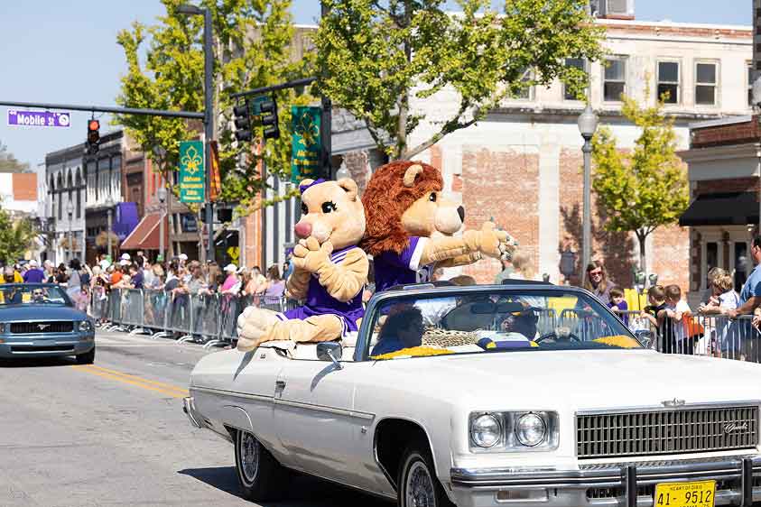 lion mascots in white convertible in parade