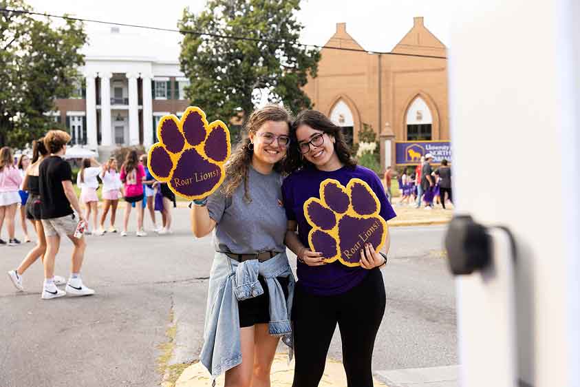 students holding large paw print cutouts