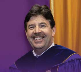 smiling man in purple graduation robes