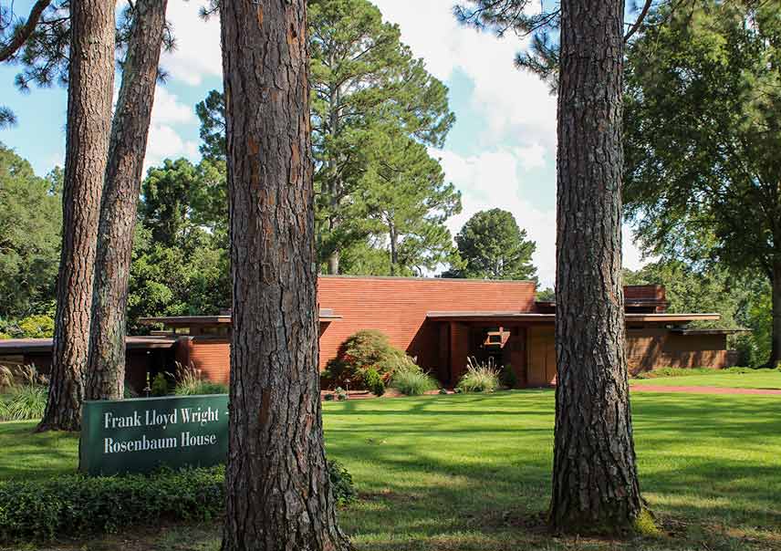 red brick Usonian home and large shade trees